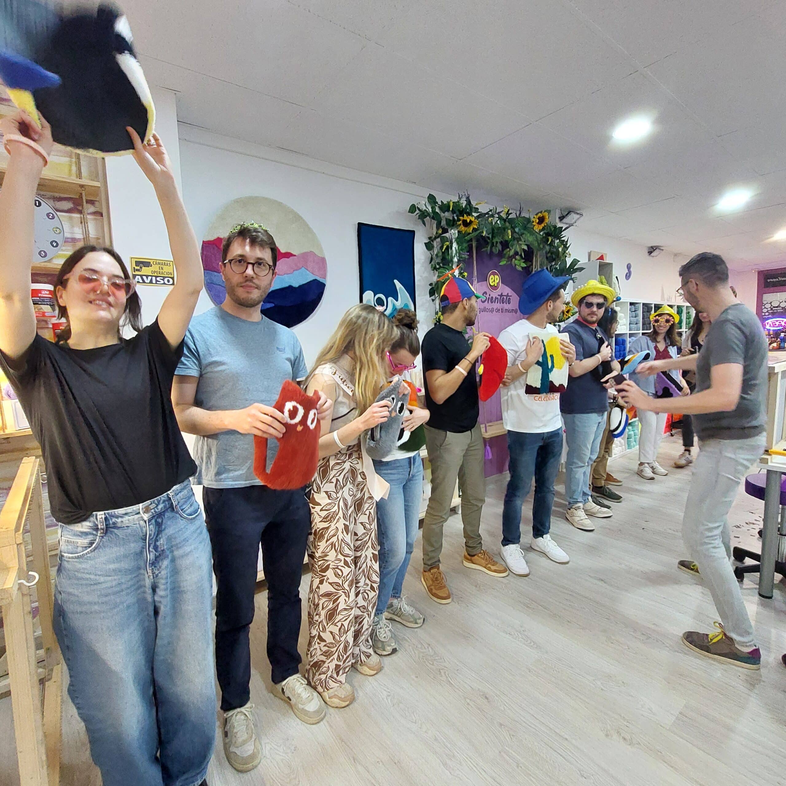 Participantes dsifrazados en fila mostrando sus alfombras terminadas