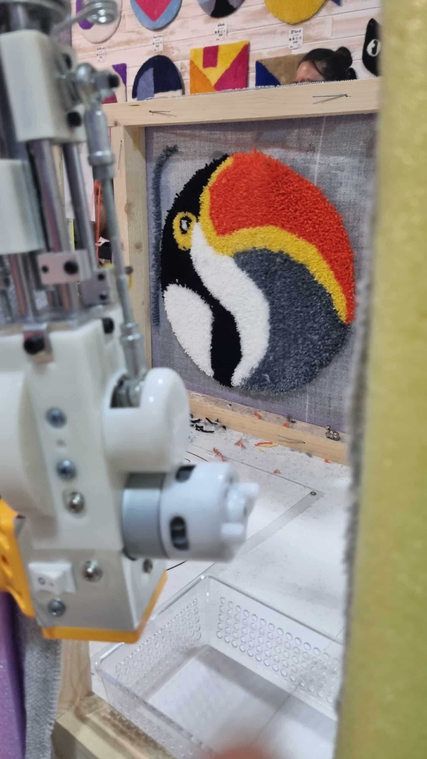 Detalle de diseño de tucán en proceso de tufting